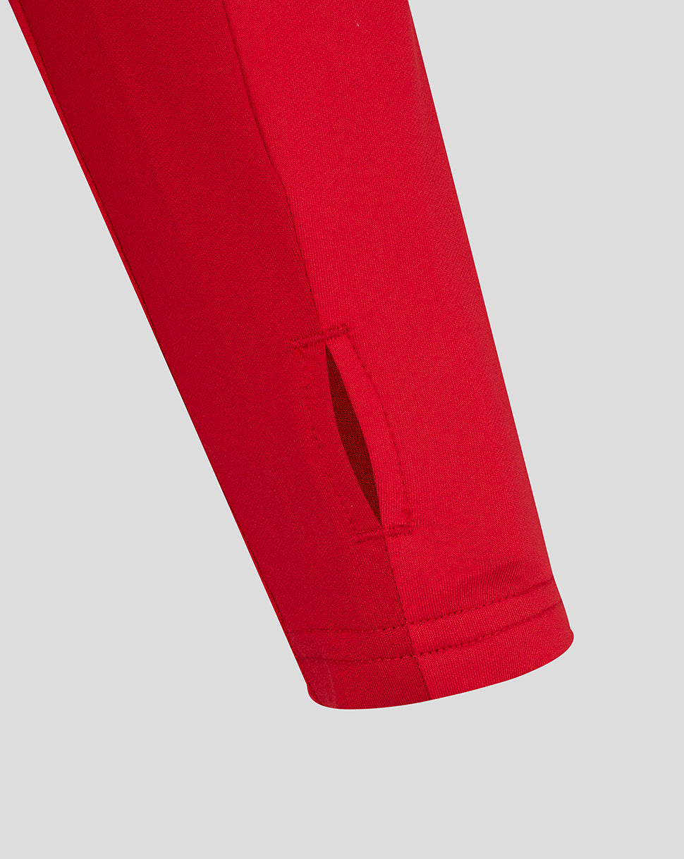 Close-up of lower sleeve showing a small slit vent at the cuff of the red training top