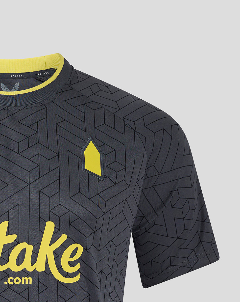 Close-up of the chest area showing the yellow crest and partial Stake sponsor on the dark geometric fabric