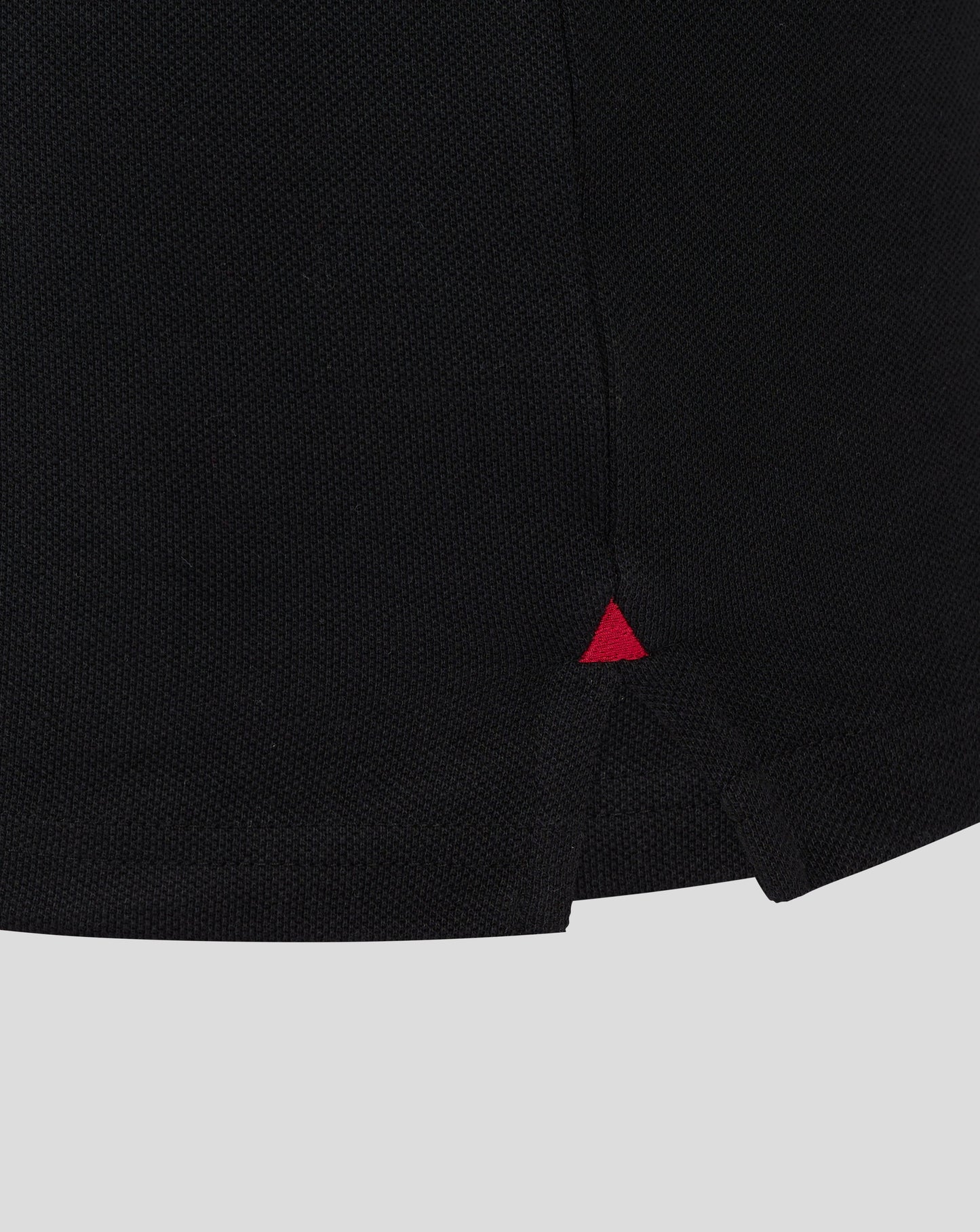 Close-up of black Rangers polo fabric showing textured knit and a small red triangle logo