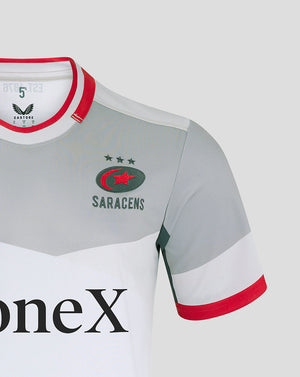 Close-up of Saracens away shirt chest showing crest, grey body, white panel and red collar trim.
