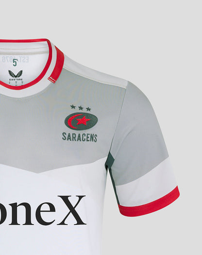 Close-up of Saracens away shirt chest showing crest, grey body, white panel and red collar trim.