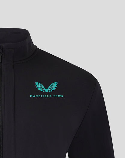 Close up of the teal Mansfield Town logo on the left chest of the black travel jacket.