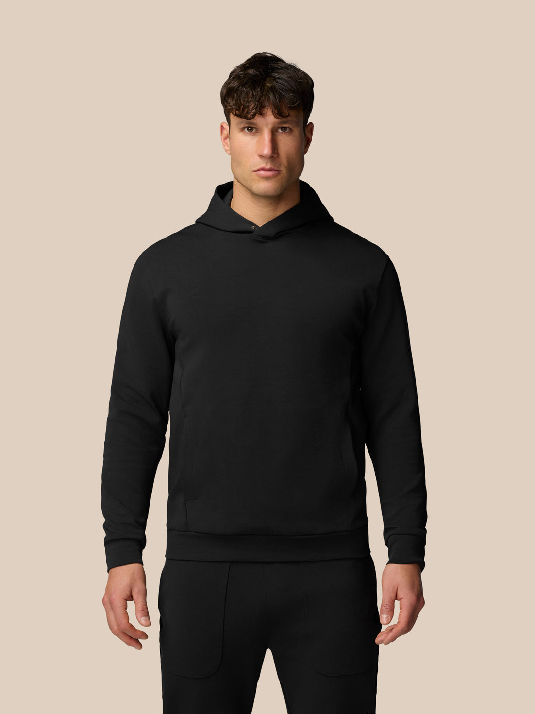 Male model wearing black Travel Logo Hoodie with relaxed fit and chest logo