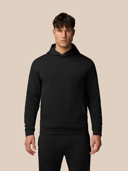 Male model wearing black Travel Logo Hoodie with relaxed fit and chest logo