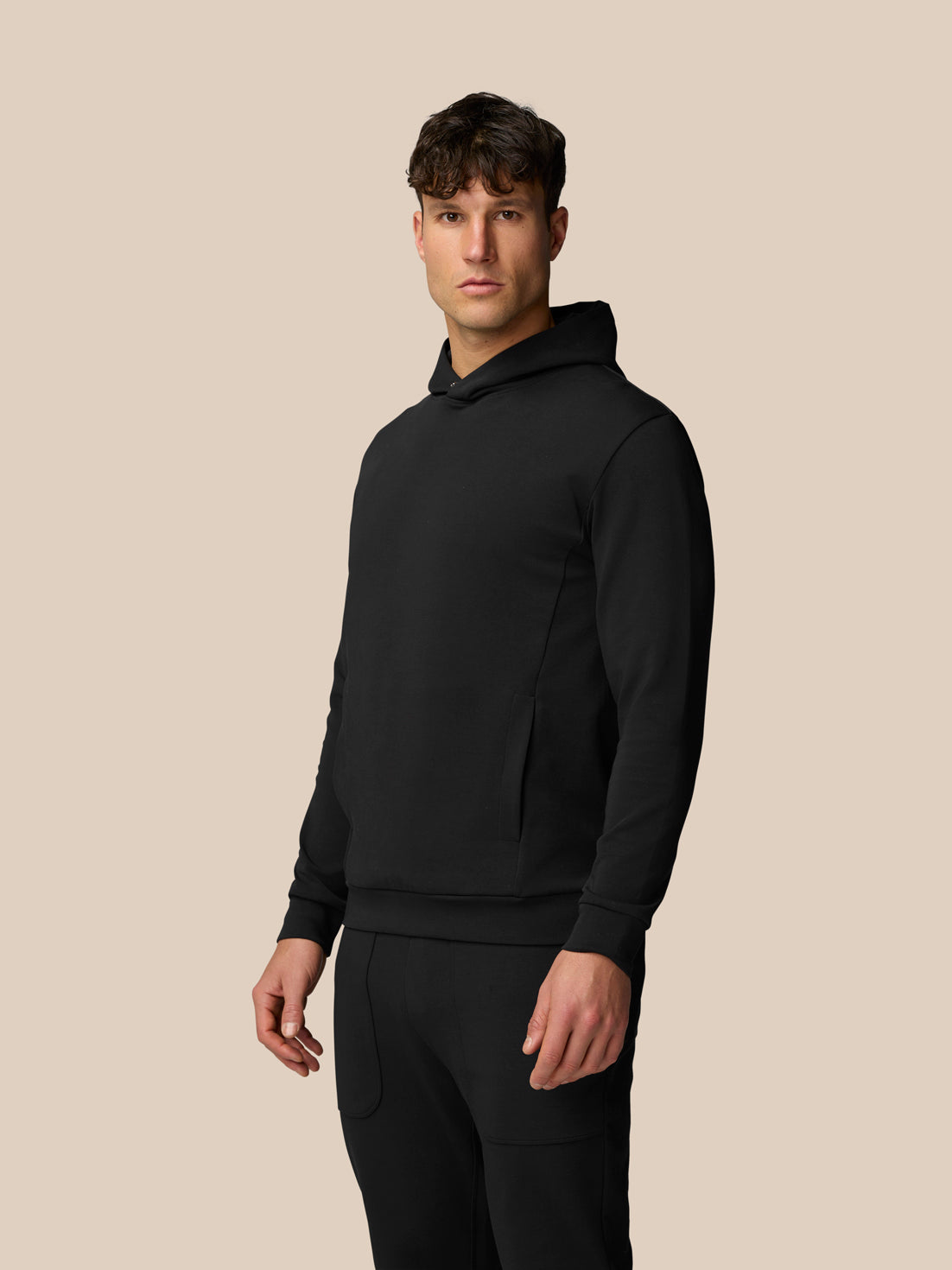 Male model wearing black Travel Logo Hoodie with relaxed fit and side pockets