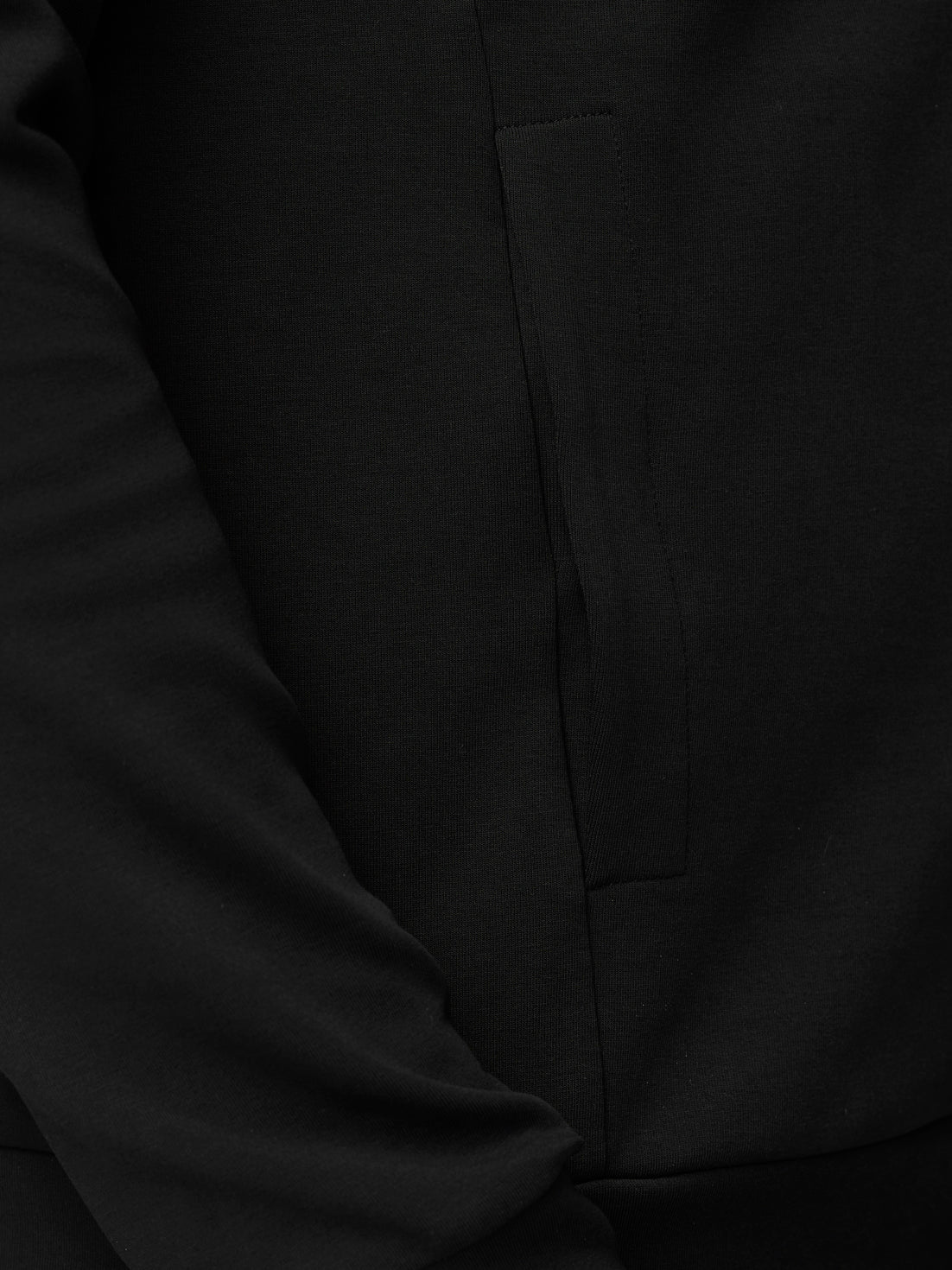 Close-up of black hoodie fabric showing the side pocket detail.