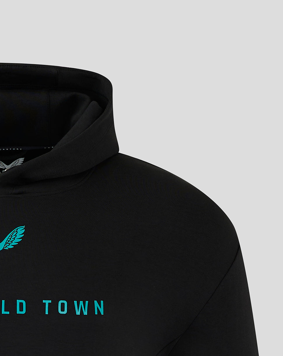 Close-up of the black Mansfield Town hoodie showing teal crest at the shoulder and teal lettering across chest