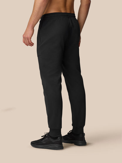 Full-length back view of a model wearing black Flex Travel Joggers with sneakers.