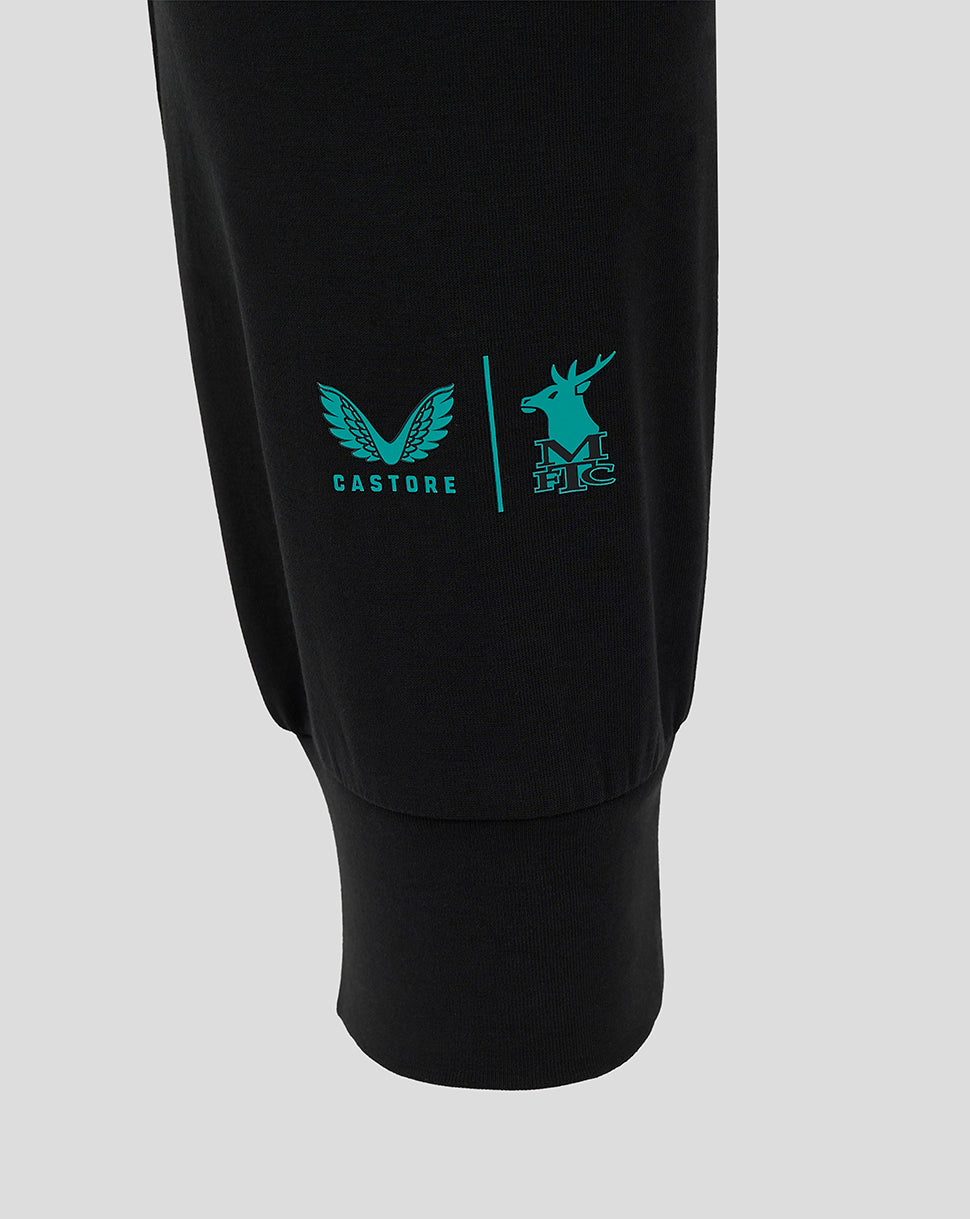 Close up of the left leg showing turquoise Castore wing logo and Mansfield Town crest on black fabric.