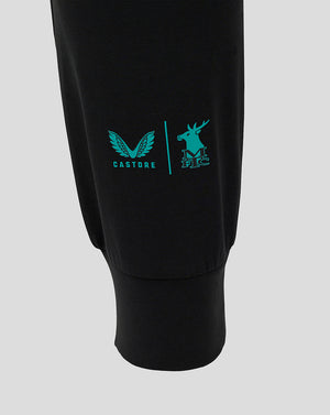 Close up of the left leg showing turquoise Castore wing logo and Mansfield Town crest on black fabric.