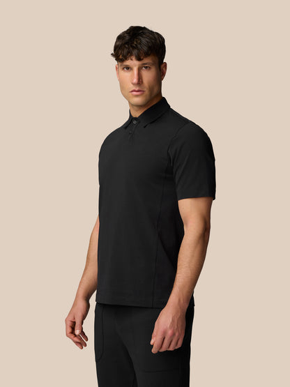 Male model in black Travel Polo standing with a slight three quarter turn, front view