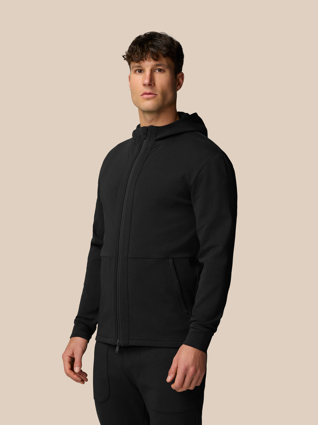Male model wearing black travel full zip hoodie with hood, front zipper, side pockets and Castore branding on left chest.