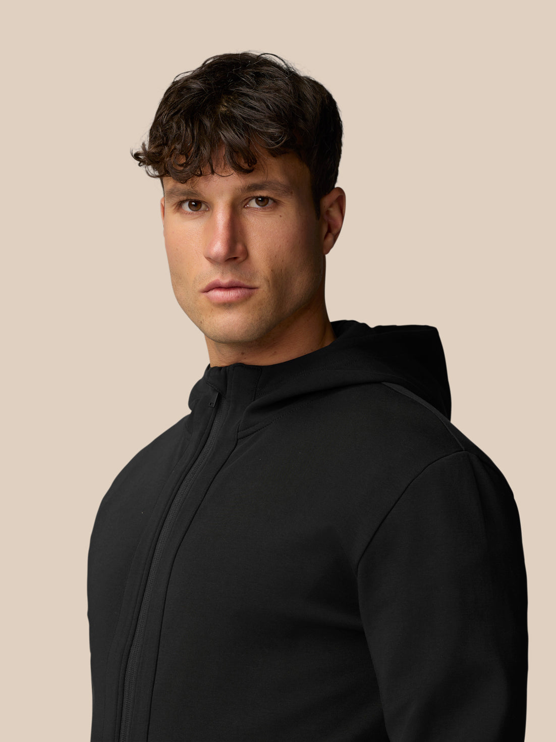 Profile view of a man in a black Travel Full Zip Hoodie with hood up and full zip front
