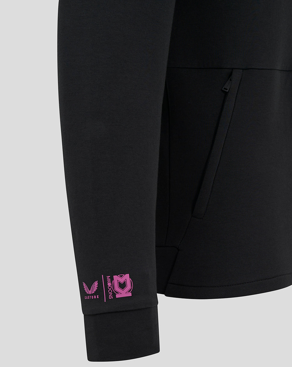 Close-up of black jacket sleeve with pink Castore and MK Dons logos near the cuff
