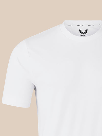 Shoulder and sleeve close-up of white short sleeve T shirt against beige background.