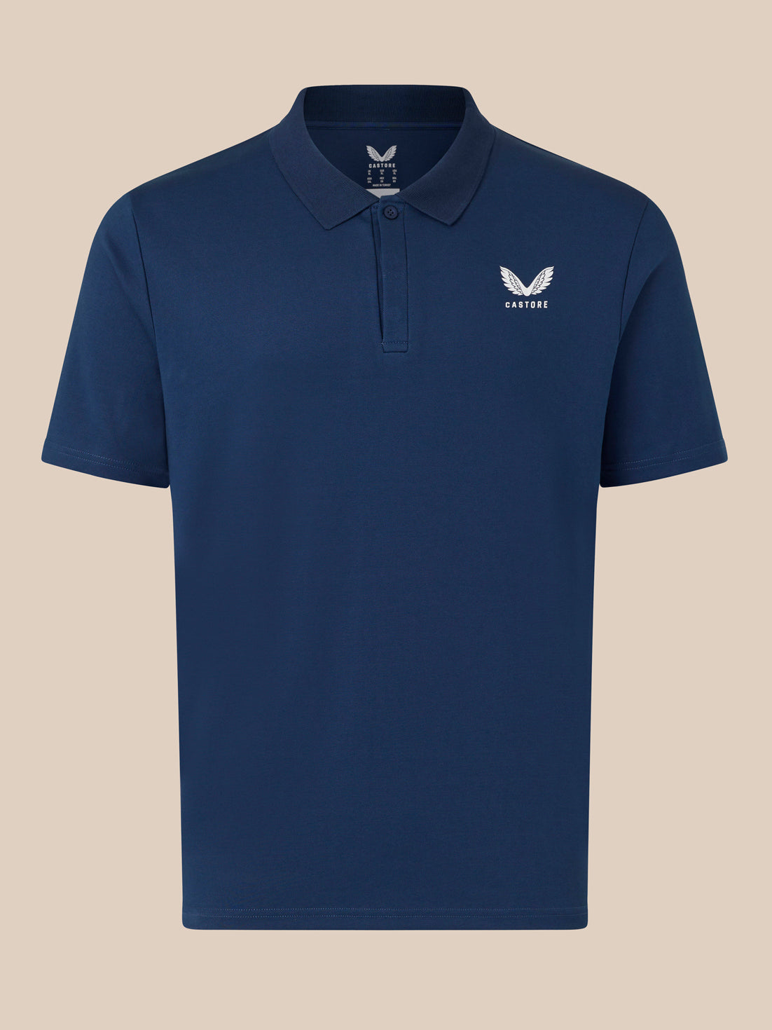 Navy Castore polo shirt front view with white wing logo on left chest on beige background