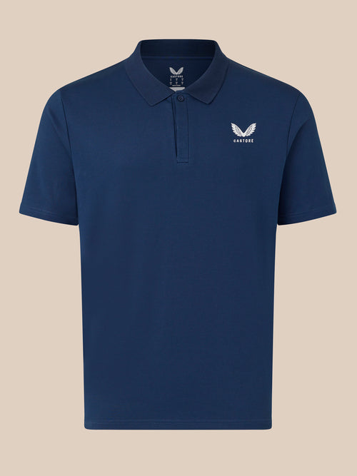 Navy Castore polo shirt front view with white wing logo on left chest on beige background