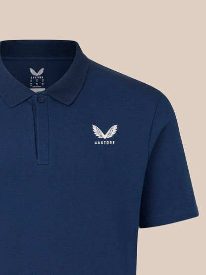 Close-up of navy polo with ribbed collar, button placket, and Castore chest logo