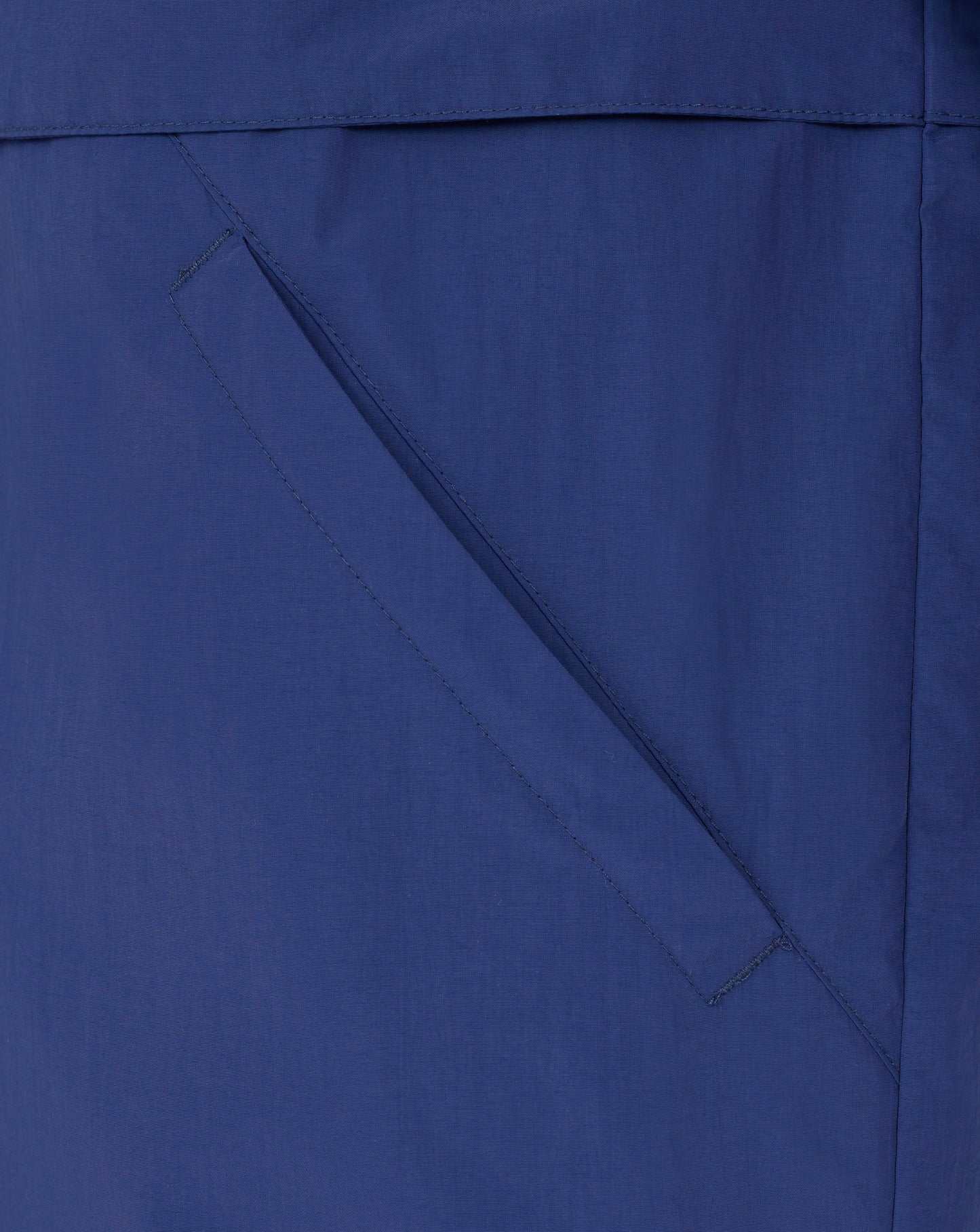Close-up of blue Rangers Men's Anorak fabric showing a diagonal pocket seam and stitching.
