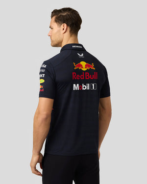 Back view of a model in a navy Red Bull Racing polo showing large Red Bull branding and sponsor decals on the back.