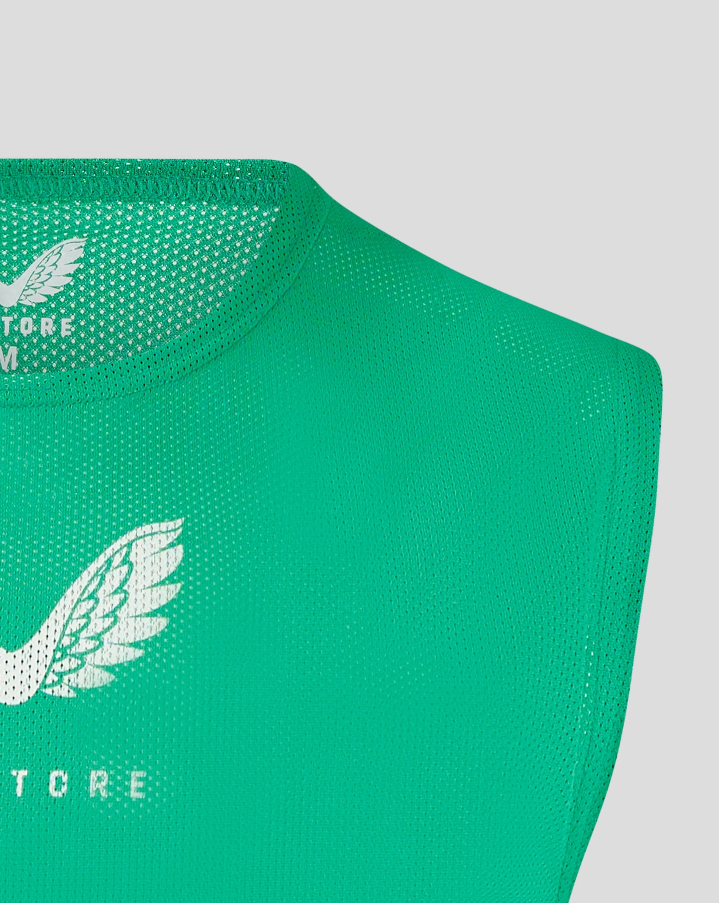 Green unisex training bib close up showing binding and Castore logo on the chest