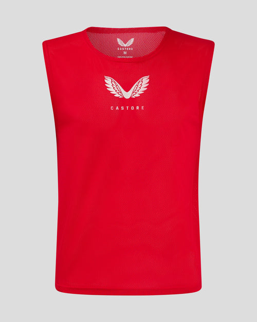 Front view of red junior training bib with white Castore wing logo on chest.
