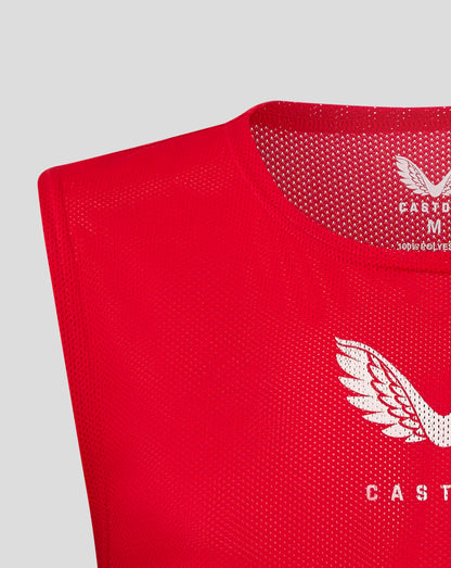 Close up of red junior training bib at the neckline and shoulder with perforated mesh texture.