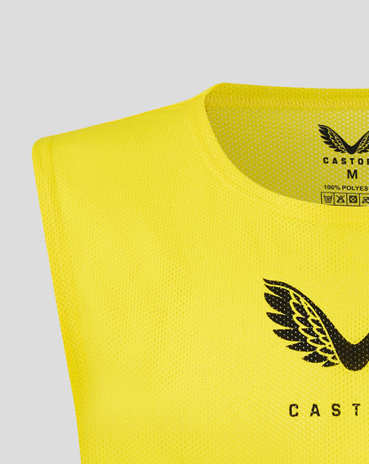 Close-up of neck opening on yellow junior training bib showing Castore branding on the inside