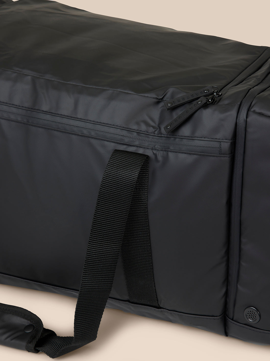 Close-up of zipper pulls labeled CASTORE on black holdall with strap detail