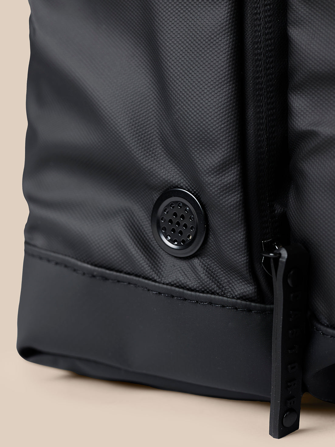 Close up of black holdall fabric showing a circular ventilation hole and edge zipper