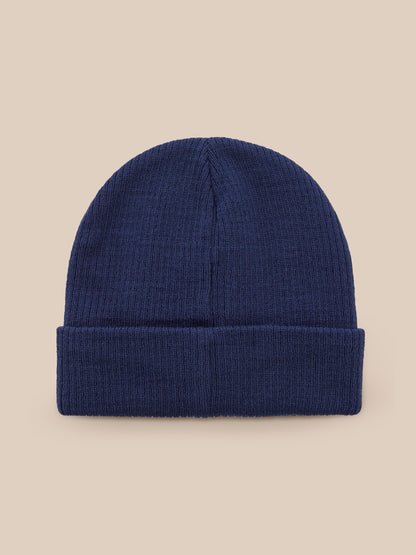 Front view of navy knit Active Beanie with folded brim against a beige background