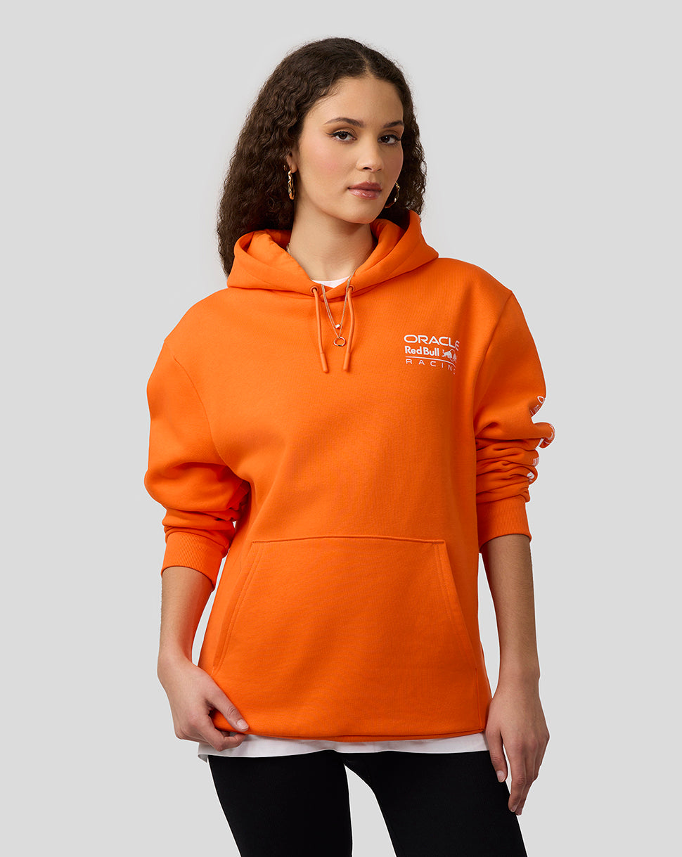 Female model in bright orange Oracle Red Bull Racing hoodie with chest logo and hood.