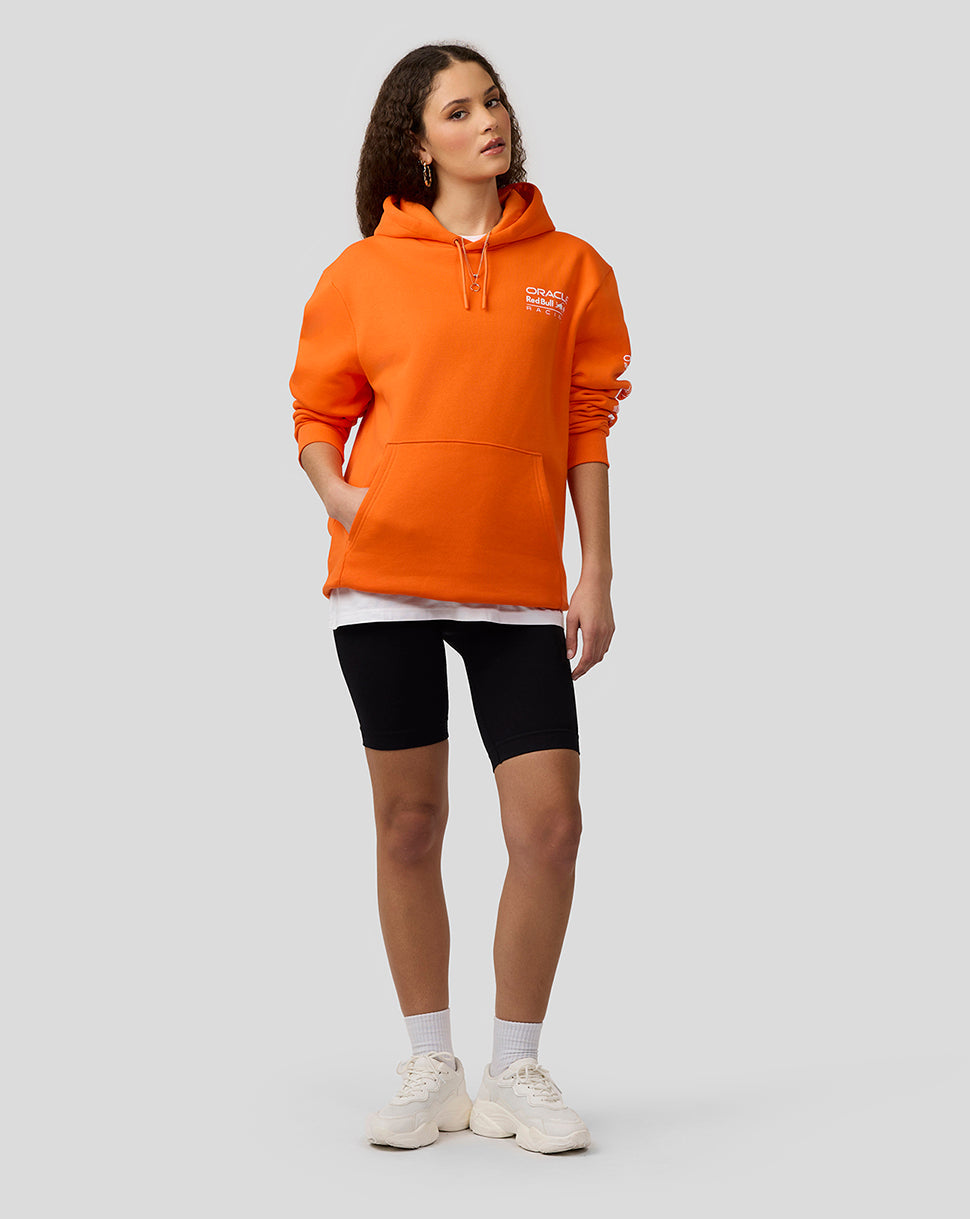 Model wearing bright orange Oracle Red Bull Racing Max Verstappen puzzle pullover hoodie with a front kangaroo pocket.