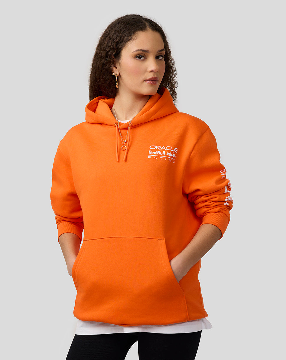 Female model wearing bright orange Oracle Red Bull Racing hoodie with front kangaroo pocket and drawstring hood.