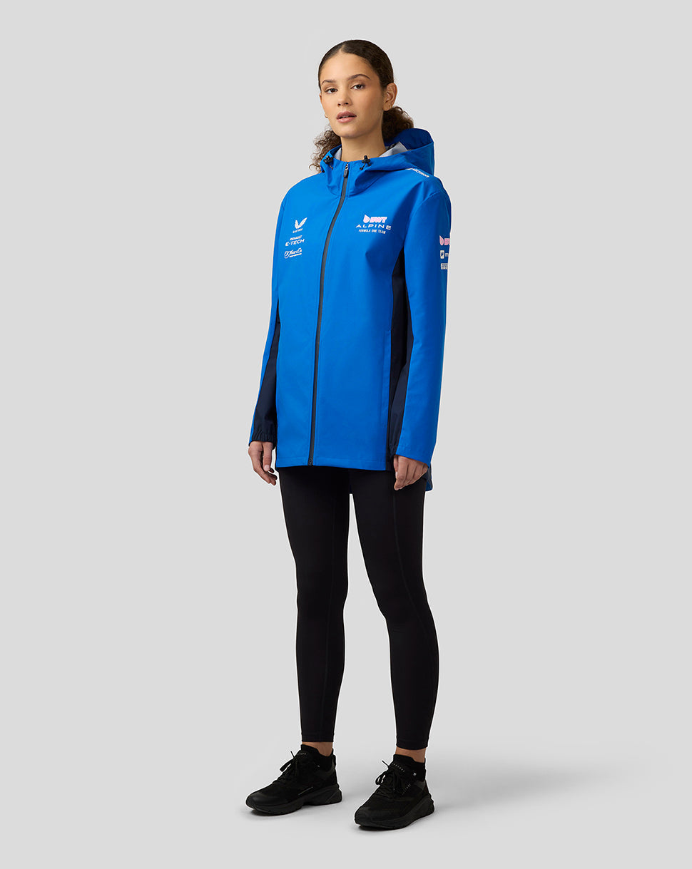 Female model in lapis blue BWT Alpine water resistant jacket with hood and front zip, featuring sponsor logos on chest