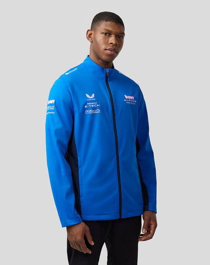 Man wearing lapis blue BWT Alpine Formula One Team unisex soft shell jacket with funnel neck and front zip, sponsor logos.