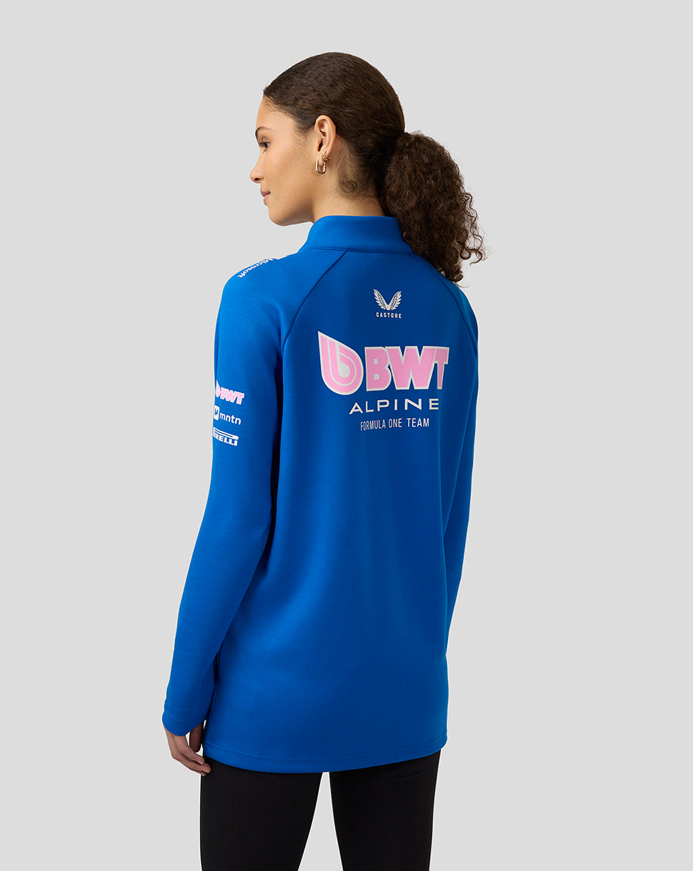 Back view of a woman wearing a blue BWT Alpine midlayer with a large back logo and sponsor logos on the sleeves