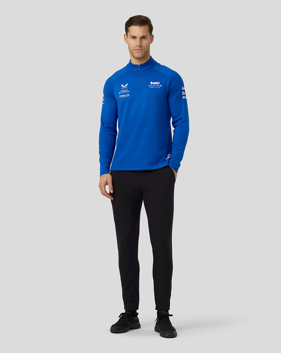 Front view of a man wearing a blue BWT Alpine quarter zip midlayer with logos on the chest