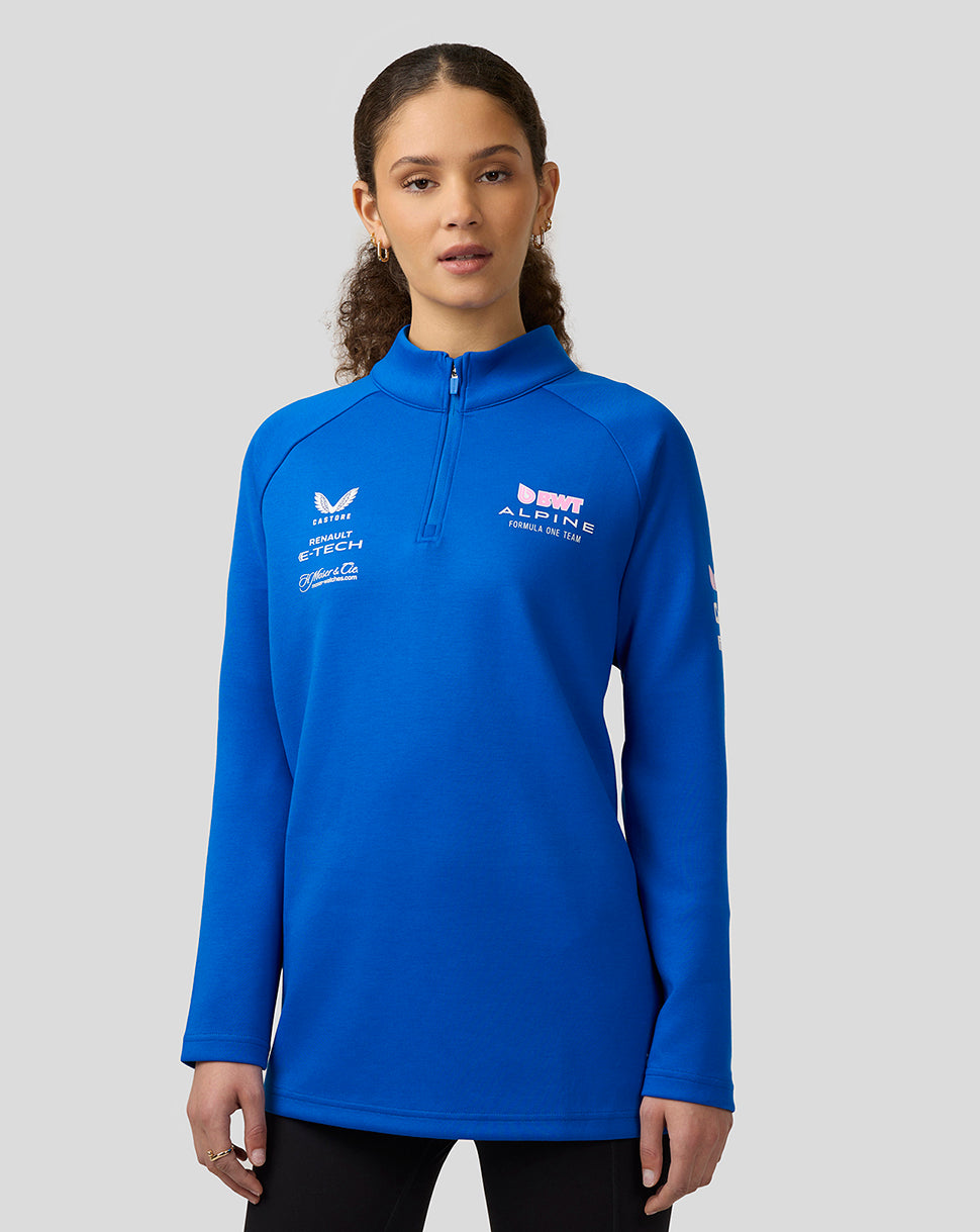 Female model in blue BWT Alpine Formula One Team quarter zip mid layer with funnel neck and chest logos.