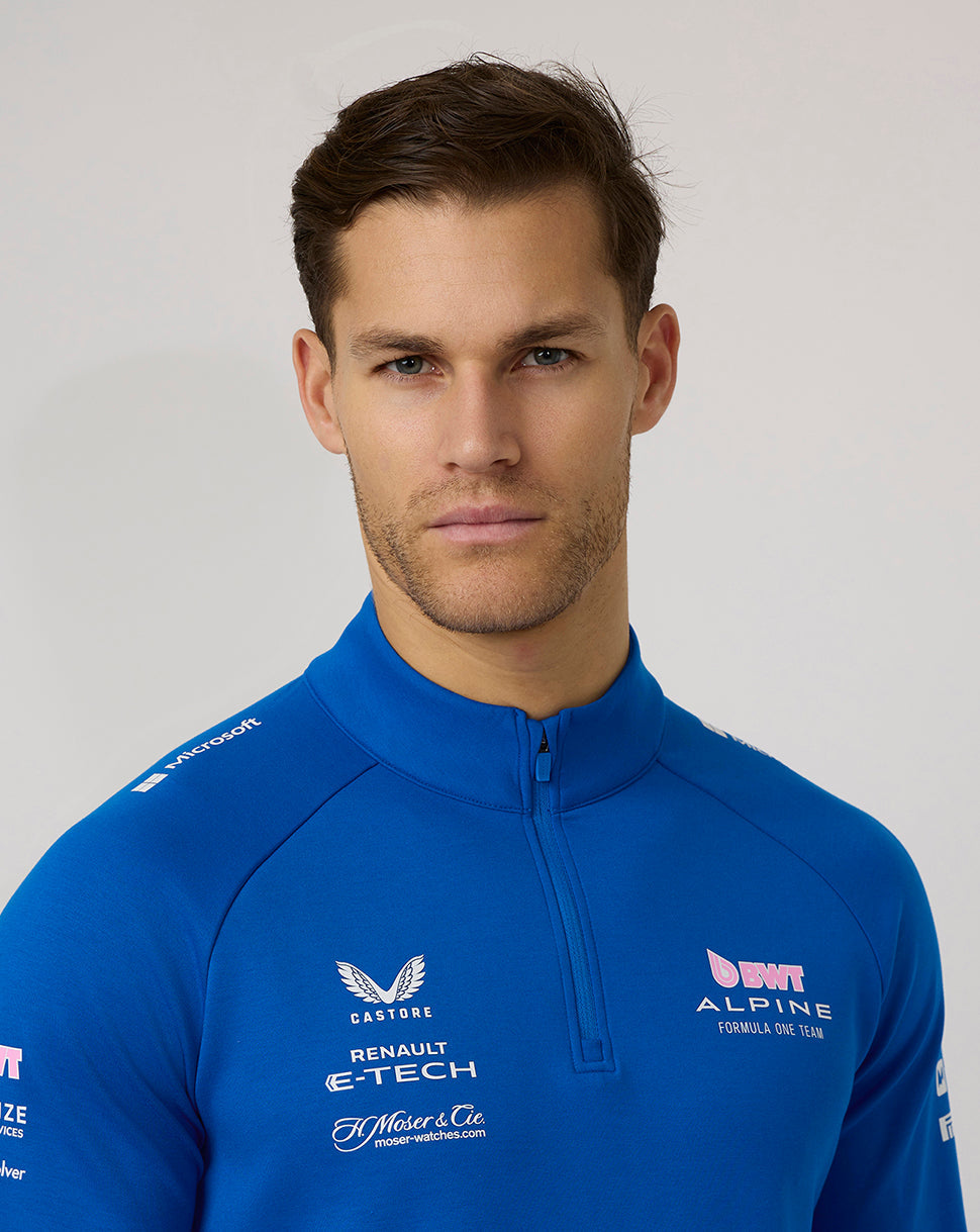 Close-up of man in lapis blue BWT Alpine quarter zip midlayer with chest logos.