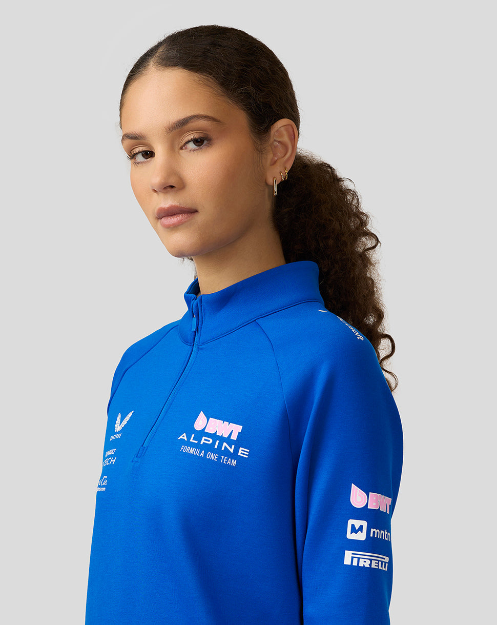 Profile of woman in lapis blue BWT Alpine midlayer with chest and sleeve logos.