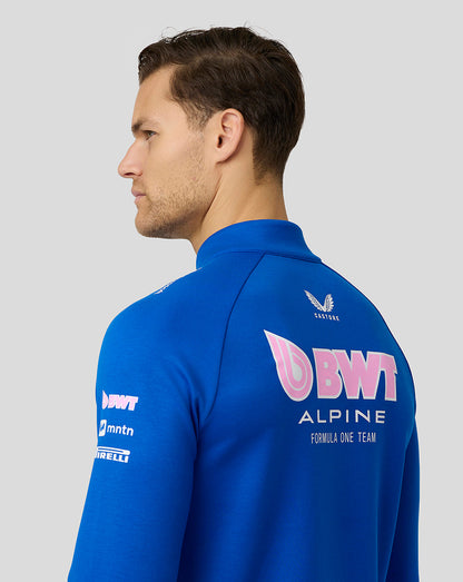 Three quarter rear view of a man in lapis blue BWT Alpine quarter zip midlayer showing a large logo on the back.
