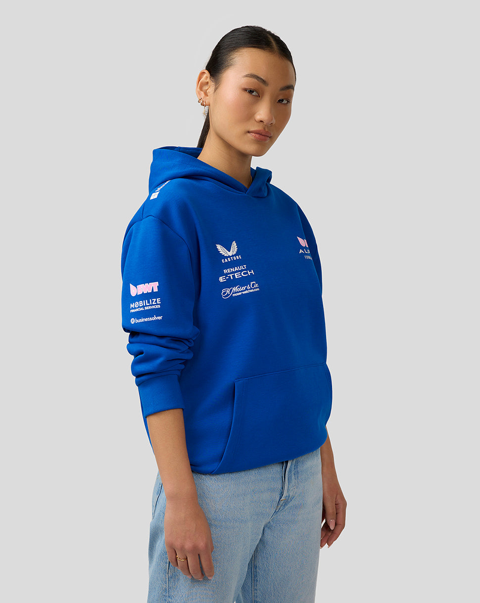 Female model wearing lapis blue BWT Alpine hoodie shown from the back with a large logo graphic on the back