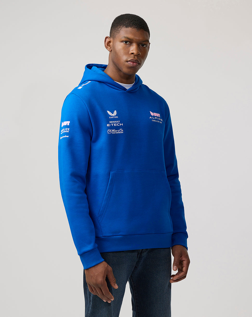 Male model wearing a lapis blue BWT Alpine Formula One Team unisex pullover hoodie with logo graphics