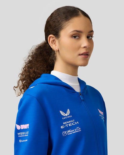 Profile view of a woman in lapis blue BWT Alpine full zip hoodie showing chest and sleeve logos