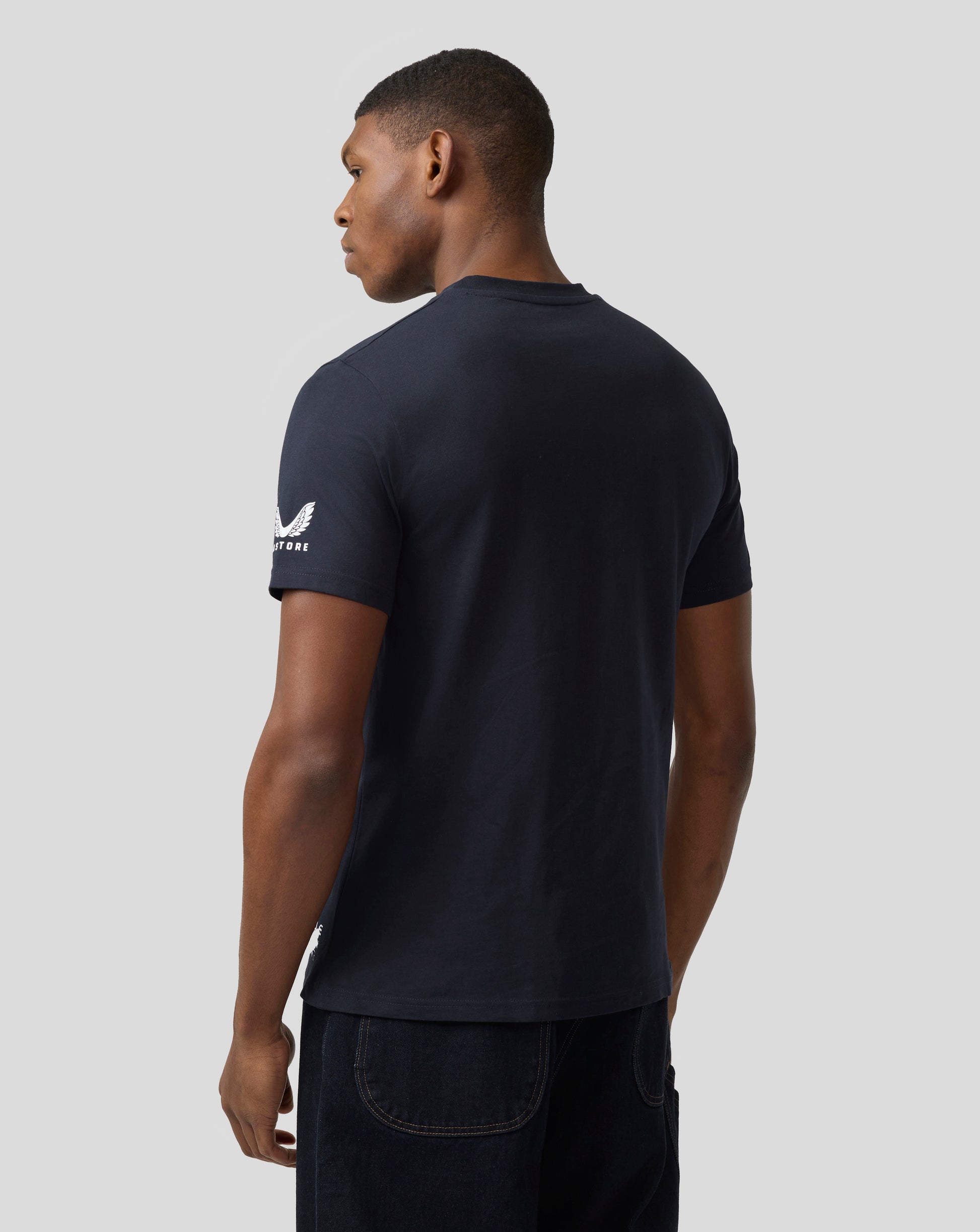 Back view of a man wearing a navy Castore T shirt displaying the white wing logo on the sleeve