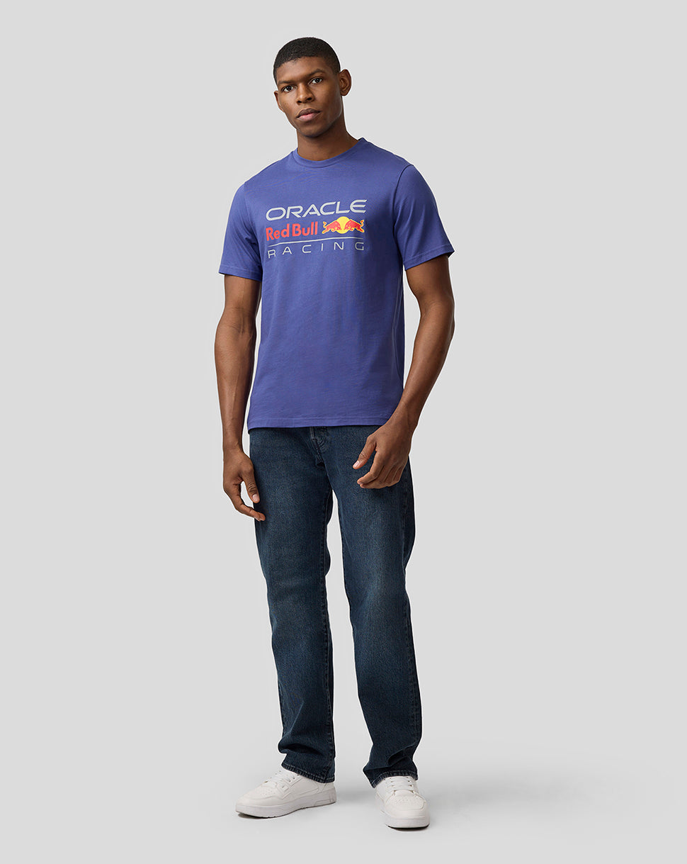 Male model wearing blue Oracle Red Bull Racing T-shirt with large front logo, paired with jeans and white sneakers.