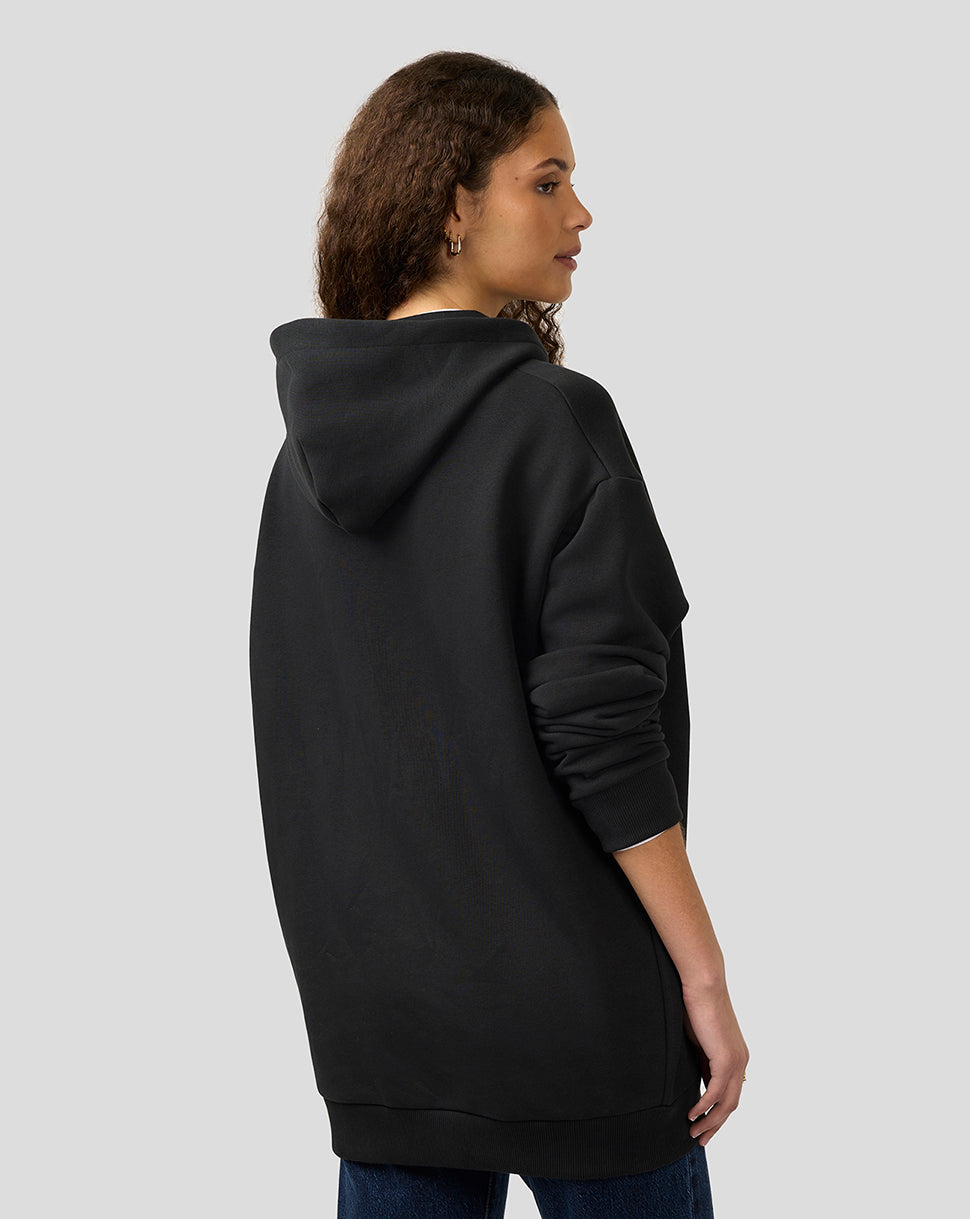Back view of a model wearing an oversized black hoodie with a hood and ribbed hem