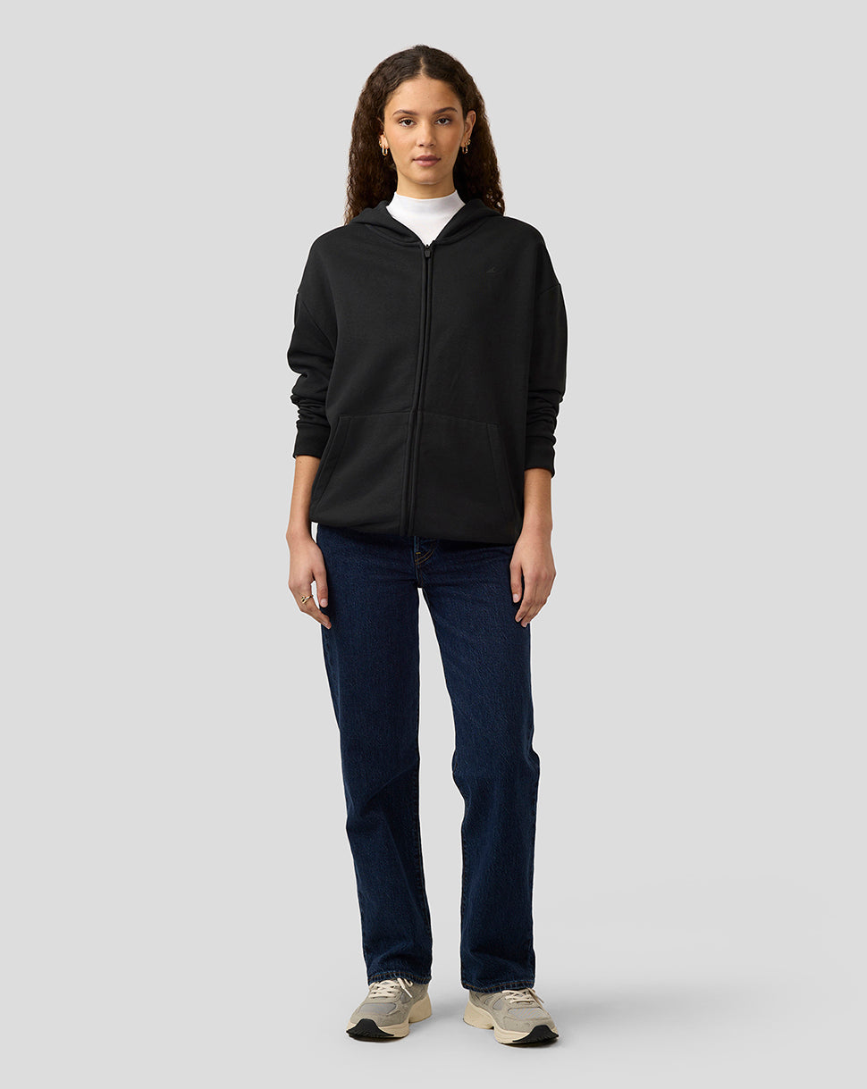 Female model wearing a black zip hoodie with front zipper and pockets, paired with jeans