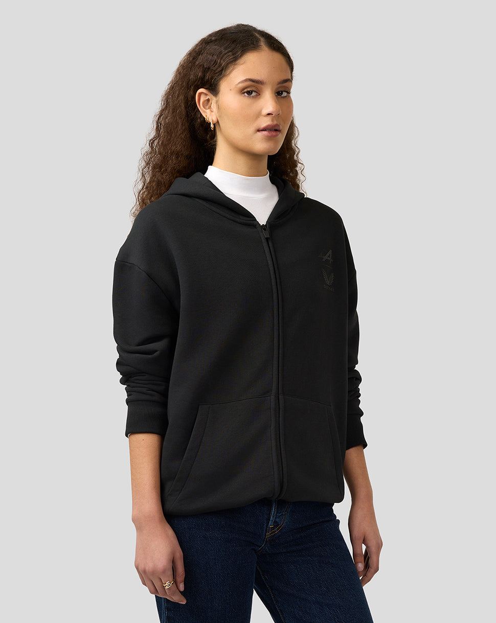 Female model wearing black unisex zipped hoodie with subtle chest logo